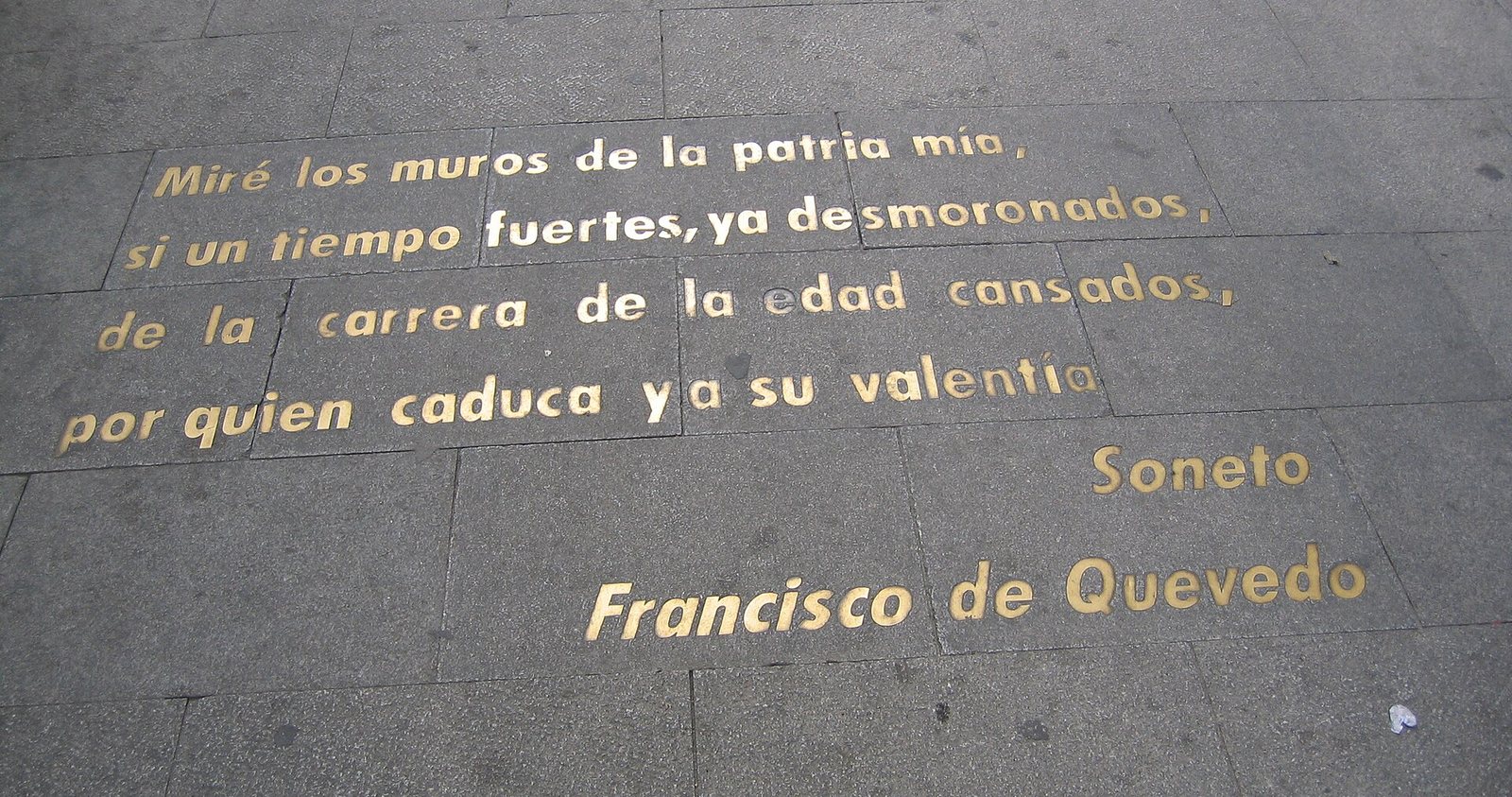 Versos de Francisco de Quevedo en letras de bronce sobre el pavimento