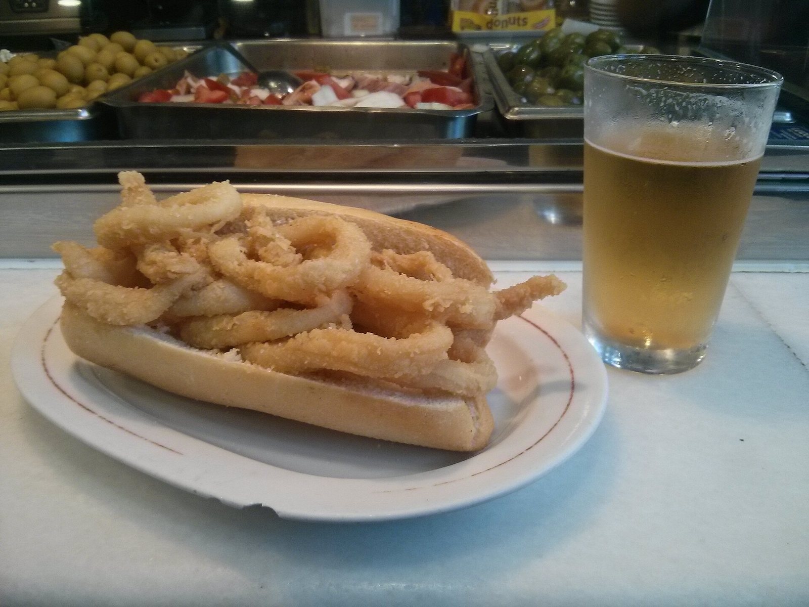 Bocadillo de calamares fritos junto a una caña de cerveza en una barra madrileña