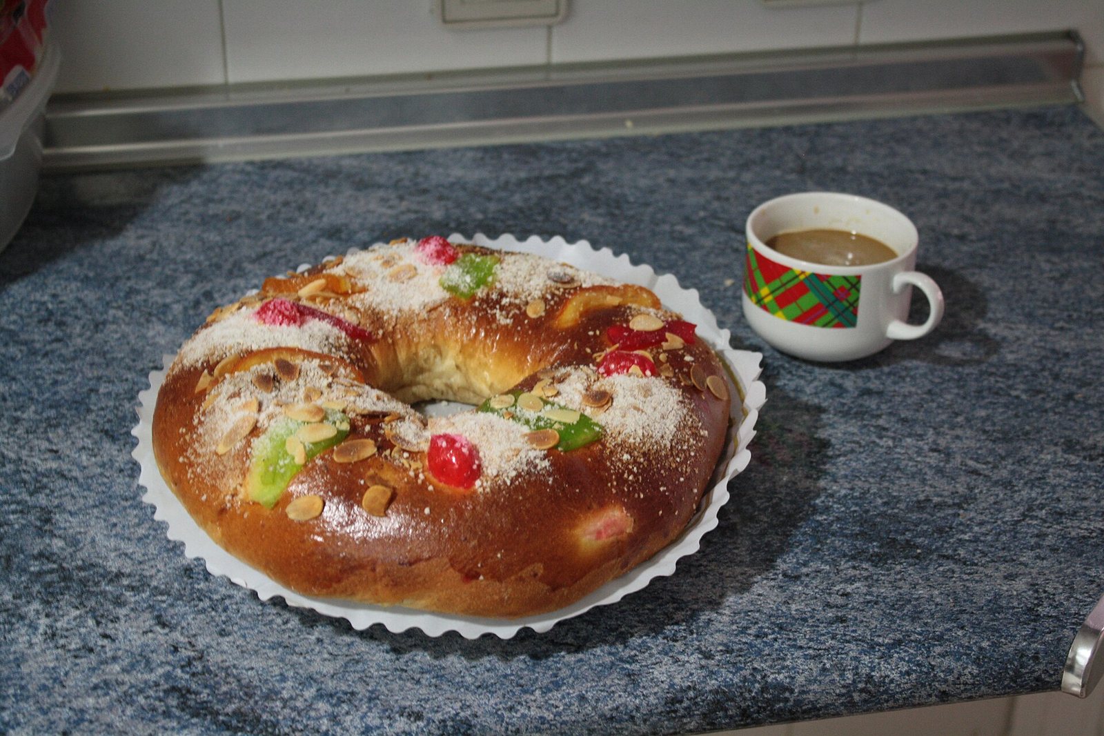 Roscón de Reyes sin relleno con fruta confitada junto a una taza de café
