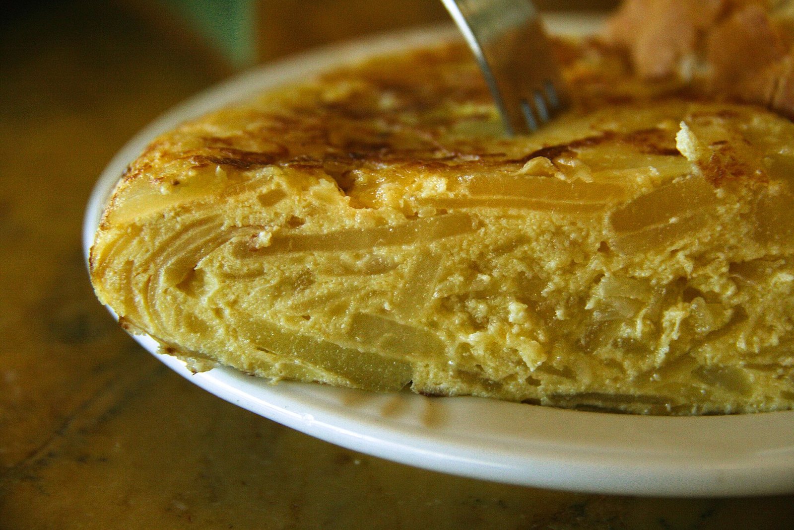 Tortilla de patatas cortada que muestra las capas de patata y el interior cuajado