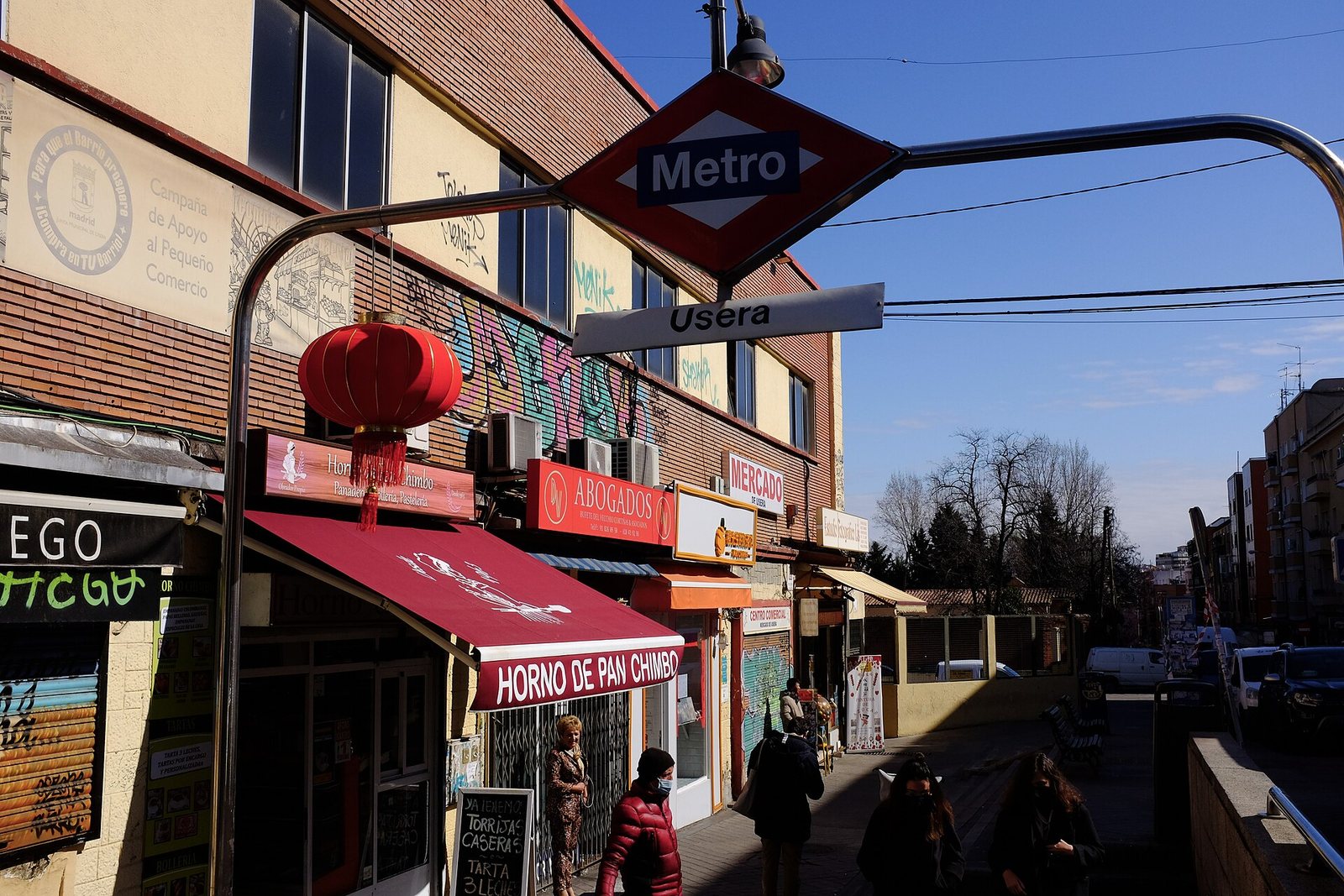 Boca de metro de Usera con un farol rojo chino junto a comercios